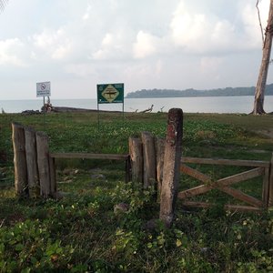 Photo contains a barricade on land just before the sea with a sign that says, ‘Danger. Crocodiles. No swimming.’