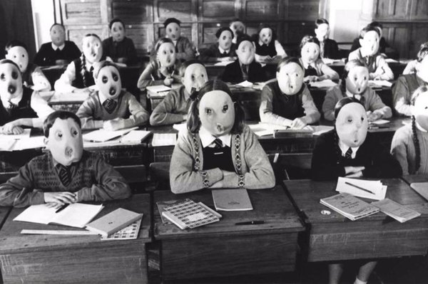 Image of children at their desks in school wearing masks devoid of expression